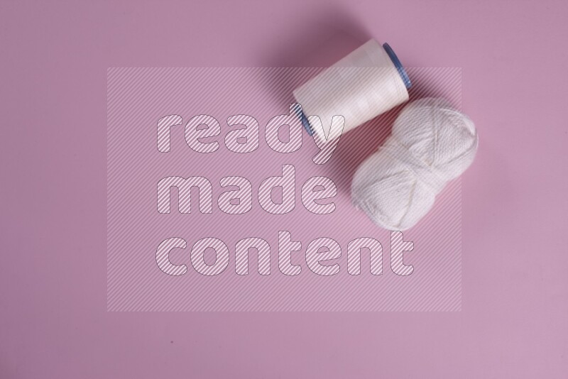 مجموعة من أدوات الخياطة والتفصيل بيضاء وزهرية اللون على خلفية زهرية