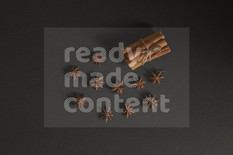 Cinnamon sticks stacked and bounded and star anise on black background