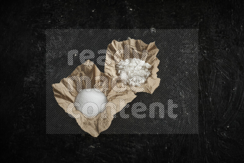 قطعة ورق مجعدة ممتلئة بالملح الأبيض على خلفية سوداء