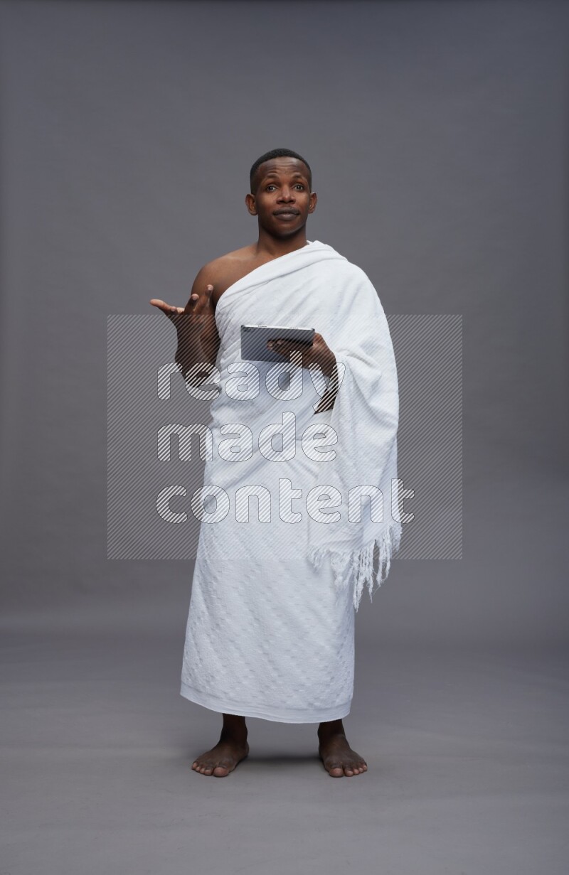 A man wearing Ehram Standing working on tablet on gray background