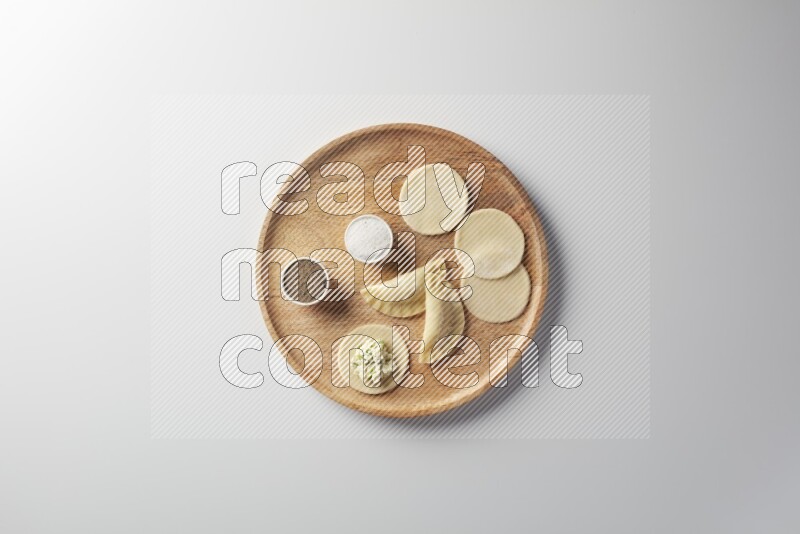 two closed sambosas and one open sambosa filled with cheese while salt, and black pepper aside in a wooden dish on a white background