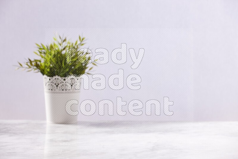 Artificial plant in white decorative pot on grey marble background