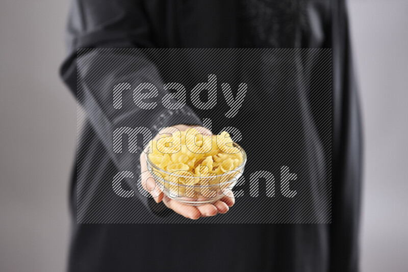 Woman in abaya holding different kinds of pasta in different positions