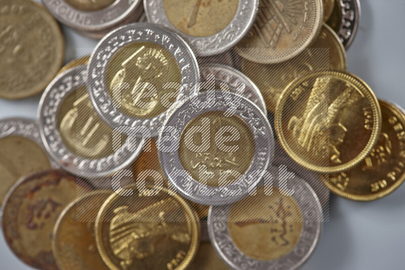 A close-up of scattered mixed Egyptian coins such as One pound, 50 and 25 piasters on grey background