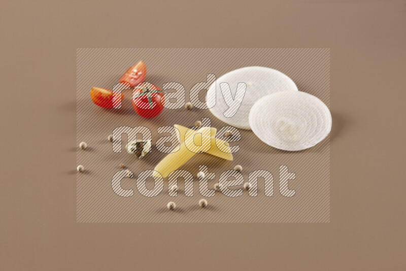 Raw pasta with different ingredients such as cherry tomatoes, garlic, onions, red chilis, black pepper, white pepper, bay laurel leaves, rosemary and cardamom on beige background