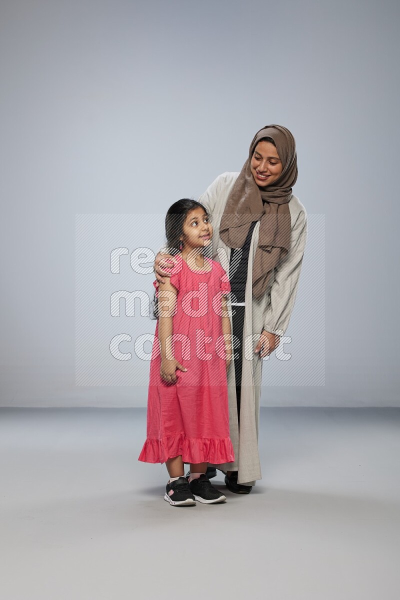 A girl and her mother interacting with the camera on gray background
