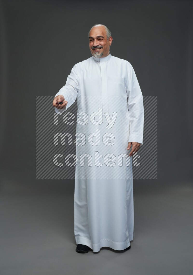Saudi man without shomag Standing holding car key on gray background