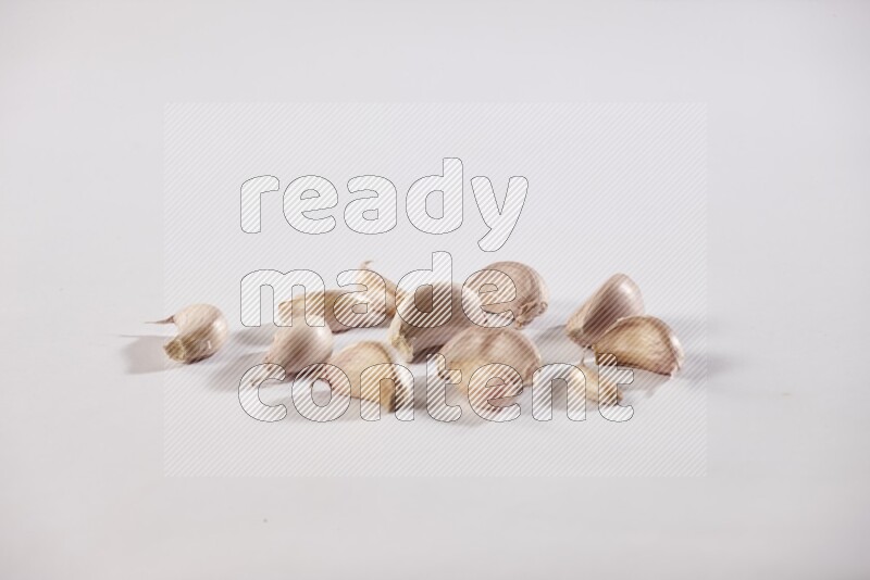 Scattered garlic cloves on a white flooring