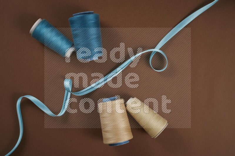 A blue collection of sewing and tailoring tools arranged on a brown background