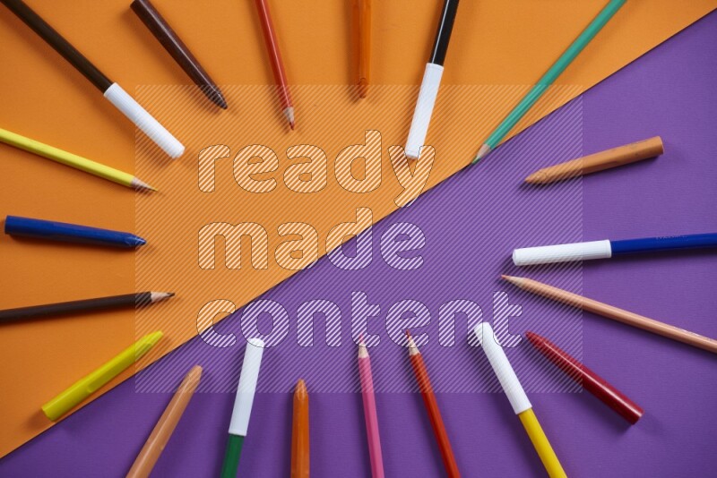 A mix of colored pencils, crayons on orange and purple background