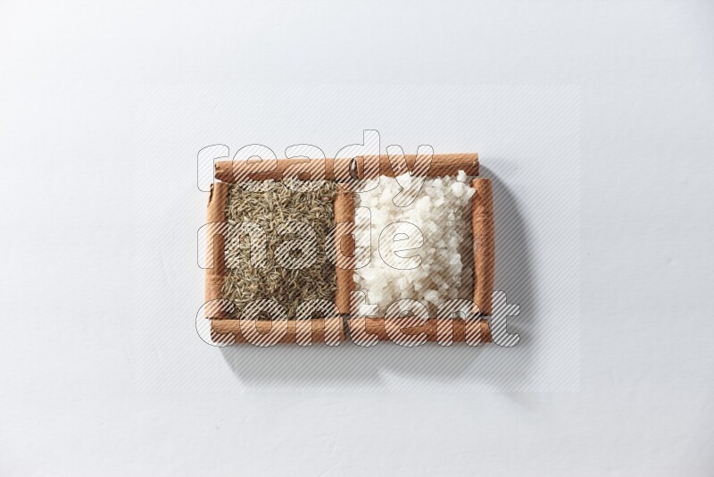 2 squares of cinnamon sticks full of white salt and cumin on white flooring