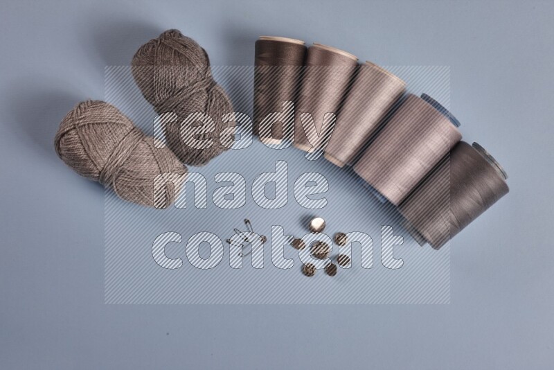 A grey collection of sewing and tailoring tools arranged on a blue background