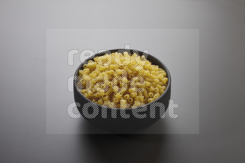 Small rings pasta in a pottery bowl on grey background