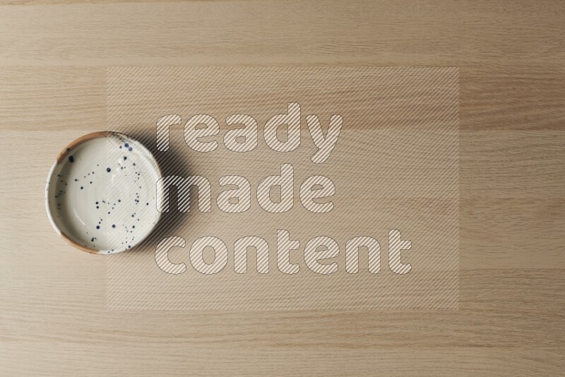 وعاء فخاري متعدد الألوان على خلفية خشبية فاتحة