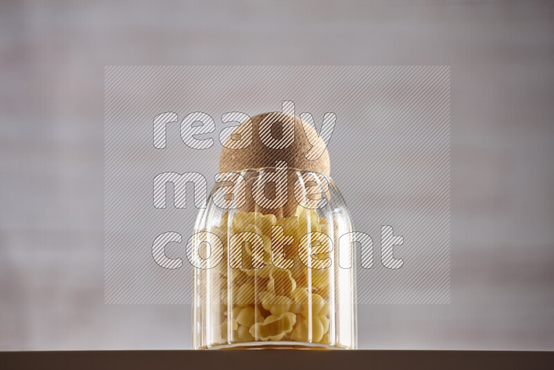 Raw pasta in glass jars on beige background