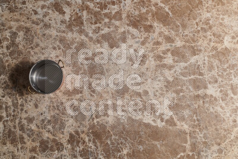 A small copper pot on beige marble background