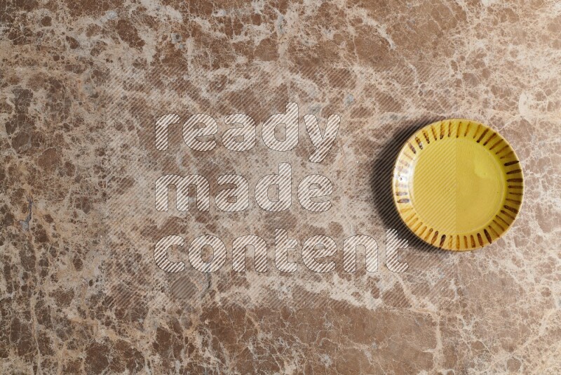 A multicolored pottery plate on beige marble background