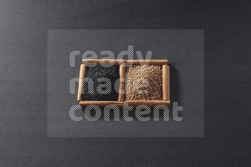 مربعان من أعواد القرفة ممتلئان بحبوب الخردل وحبة البركة السوداء علي خلفية سوداء