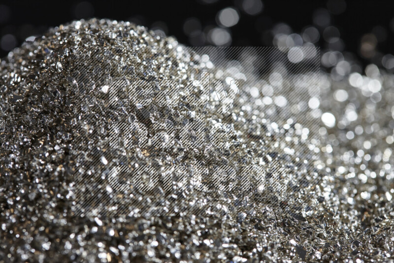 Silver shimmering fragments of glass scattered on a black background