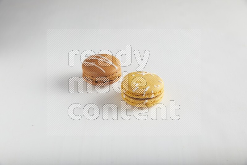 45º Shot of of two assorted Brown Irish Cream, and Yellow Piña Colada macarons on white background