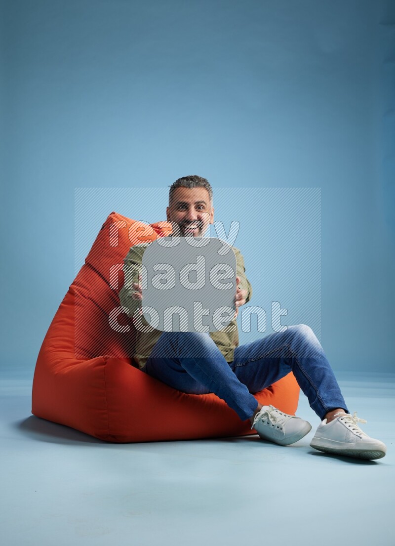 A man sitting on a orange beanbag and holding social media sign