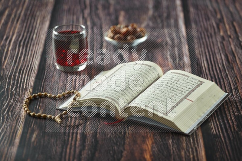 Quran with dates, prayer beads and different drinks all placed on wooden background