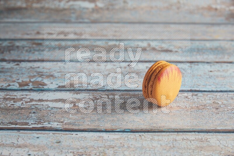 45º Shot of Orange Exotic macaron on light blue wooden background