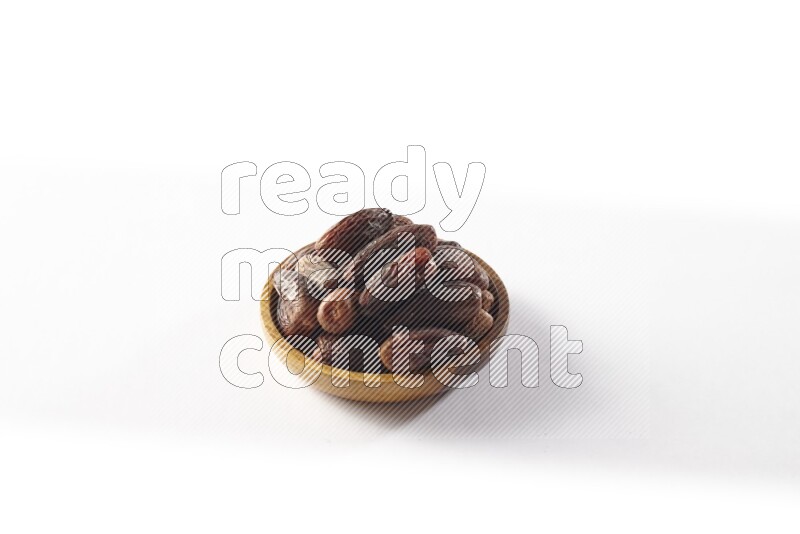 Dates in a wooden bowl on white background