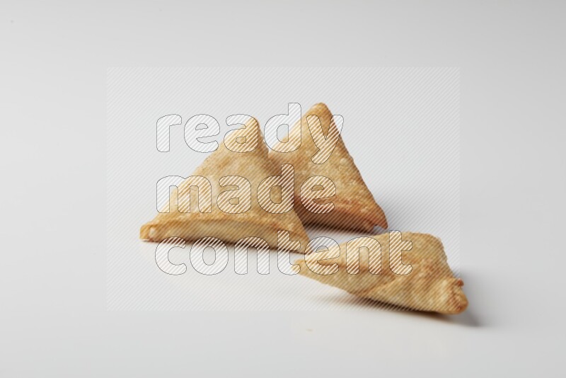 Three fried sambosas on a white background