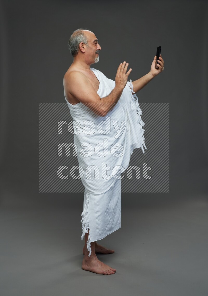 A man wearing Ehram Standing taking selfie on gray background