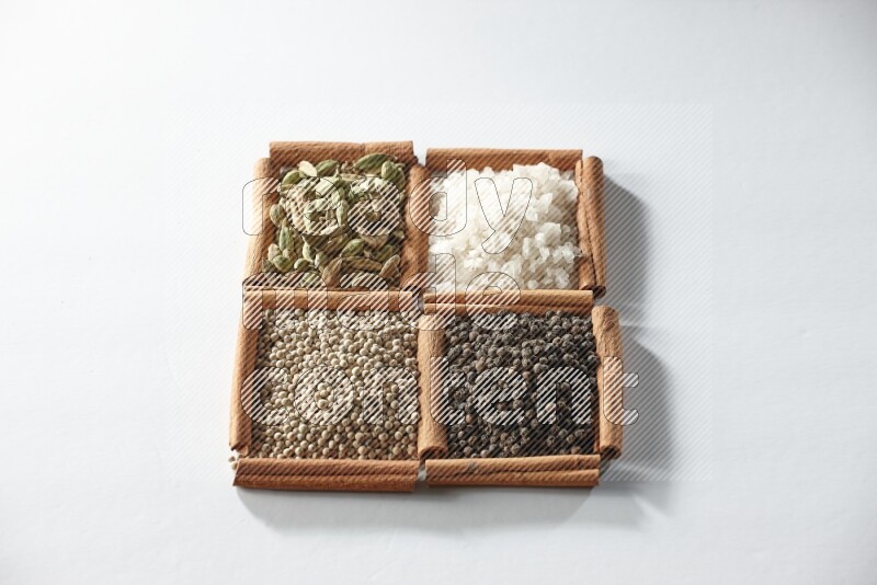 4 squares of cinnamon sticks full of cardamom, salt, white pepper and black pepper on white flooring