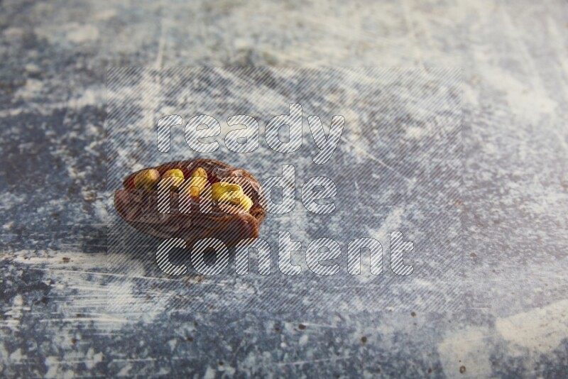 pistachios stuffed madjoul date on a rustic blue background