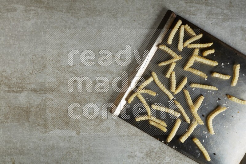 crinkle fries in a black stainless steel rectangle tray on grey textured counter top