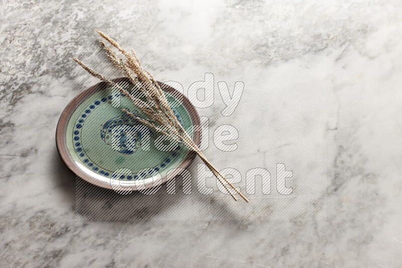 Wheat stalks on decorative pottery plate on grey marble background