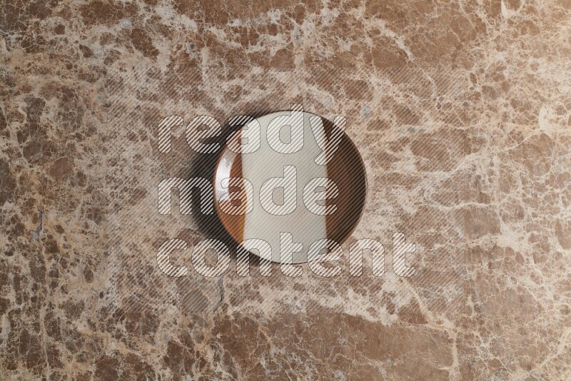 A decorative pottery plate on beige marble background