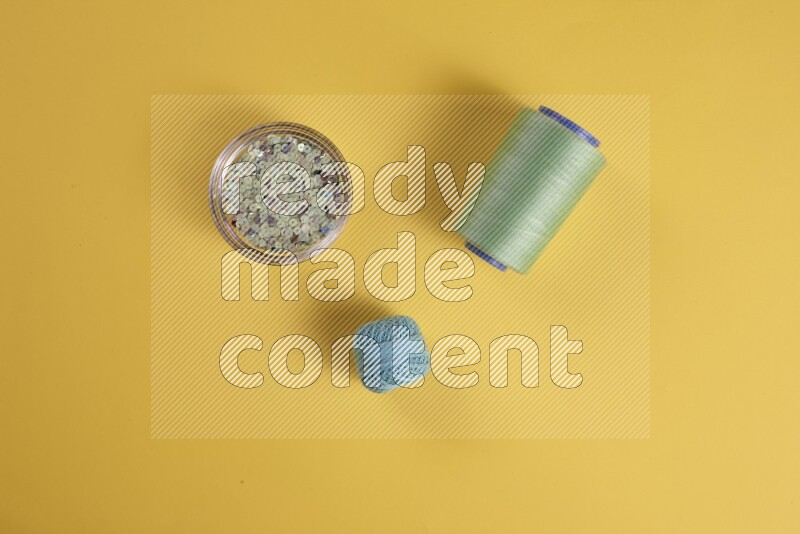 مجموعة من أدوات الخياطة والتفصيل خضراء اللون على خلفية صفراء