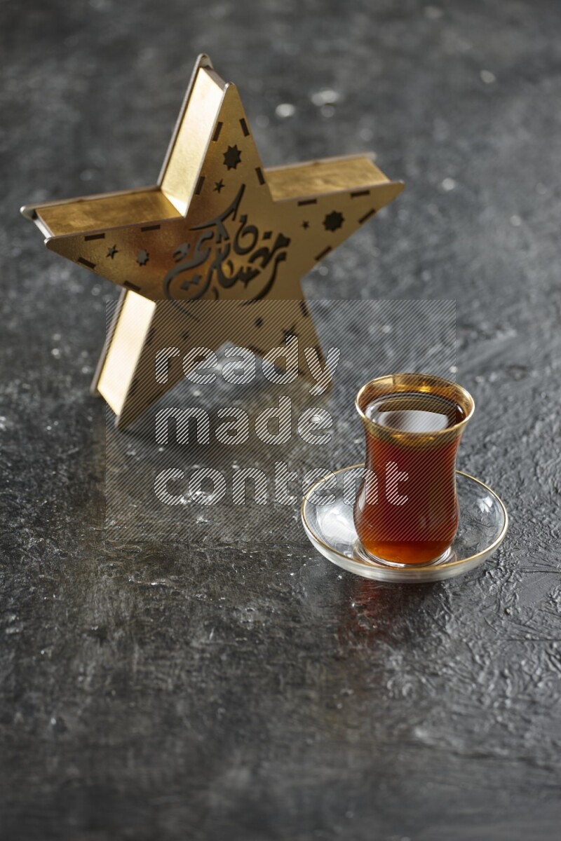 A wooden golden star lantern with different drinks, dates, nuts, prayer beads and quran on textured black background