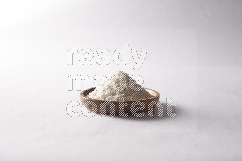 Desiccated coconuts in a wooden bowl on white background