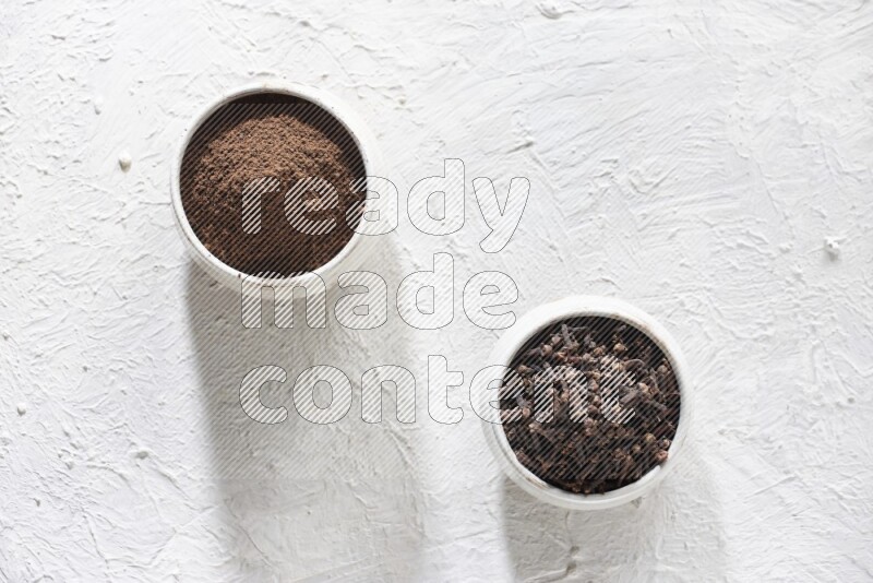 وعاءين من السيراميك بيج اللون، أحدهما مملوء بالقرنفل والآخر مملوء بالبودرة على أرضية بيضاء