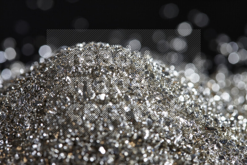 Silver shimmering fragments of glass scattered on a black background