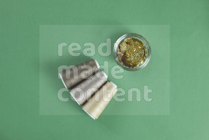 مجموعة من أدوات الخياطة والتفصيل بنية اللون على خلفية خضراء