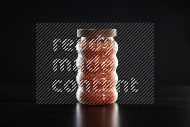 Lentils in a glass jar on black background