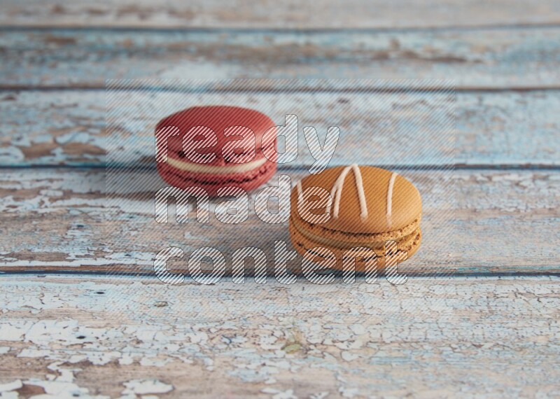 45º Shot of of two assorted Brown Irish Cream, and Red Velvet macarons on light blue background