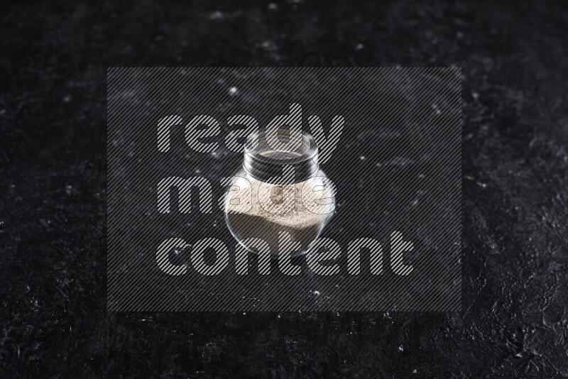 وعاء زجاجي ممتلئ ببودرة البصل علي خلفية سوداء