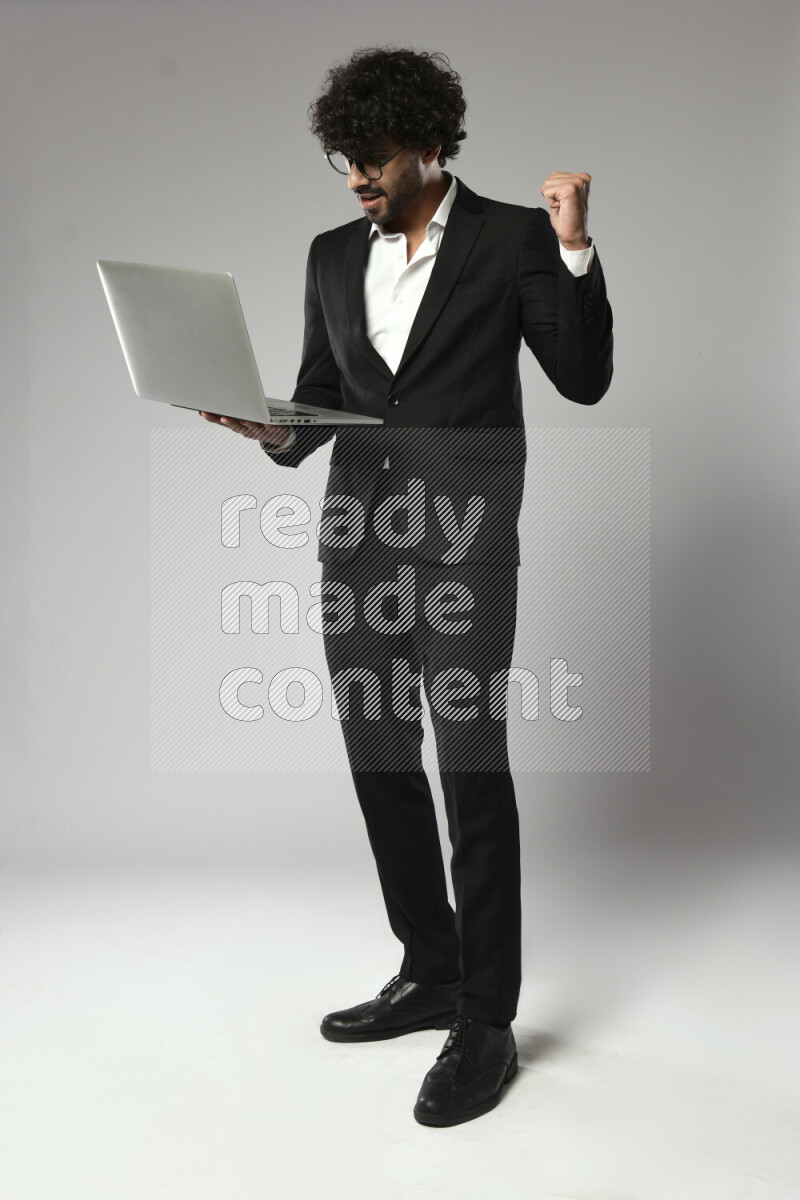 A man wearing formal standing and working on a laptop on white background