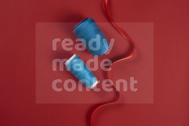 A blue and red collection of sewing and tailoring tools arranged on a red background