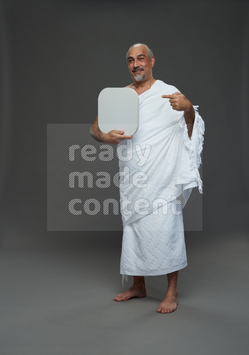 A man wearing Ehram Standing holding social media sign on gray background