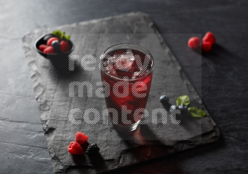 A glass of mixed berries juice on black background