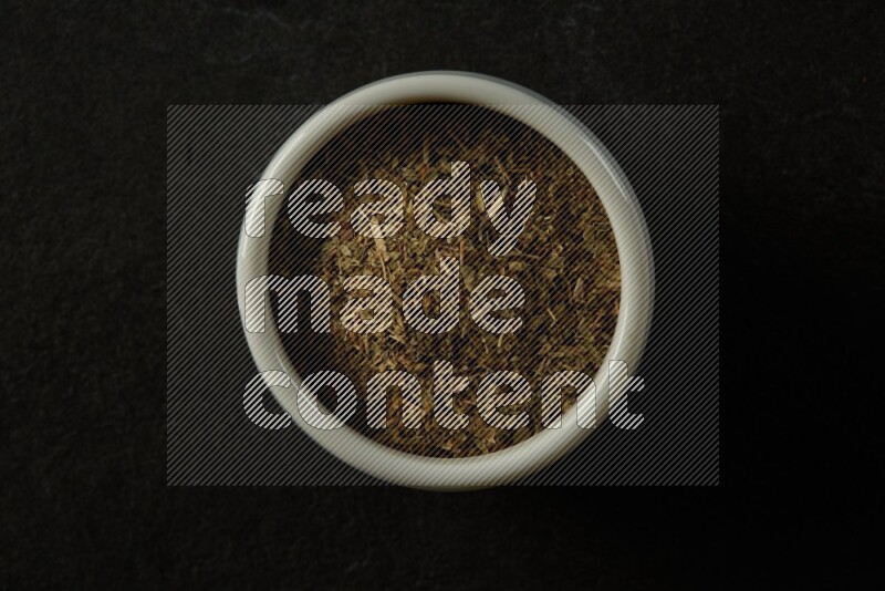 white ceramic round sauce bowl filled with herbs on grey textured countertop