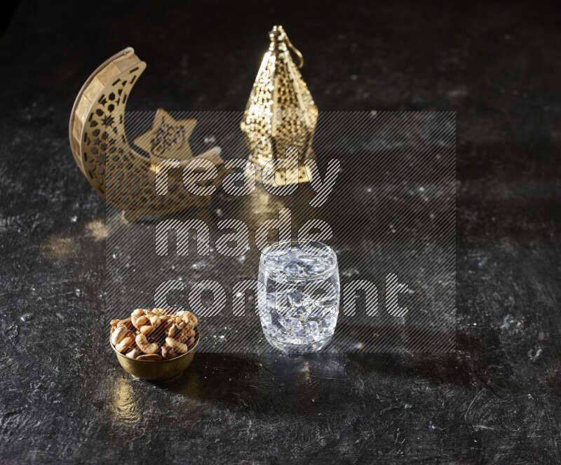 Nuts in a metal bowl with water beside golden lanterns in a dark setup